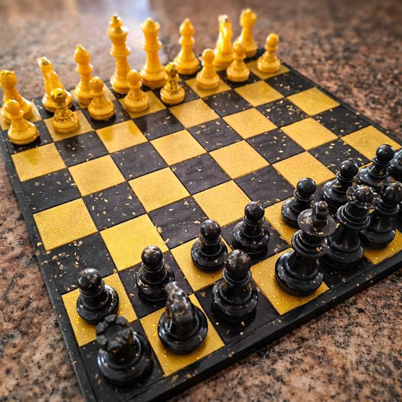Échiquier en résine noir et or fait main – plateau d’échecs artisanal START avec pièces noires et dorées